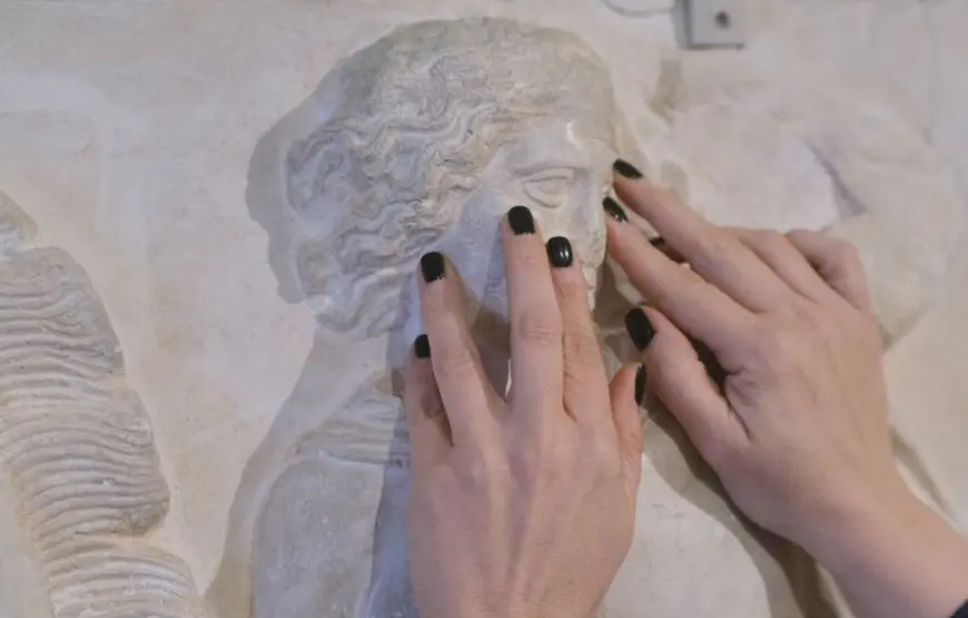 due-mani-di-donna-toccano-il-rilievo-marmoreo-durante-il-tour-in-grecia-per-non-vedenti-nel-museo-tattile-di-atene