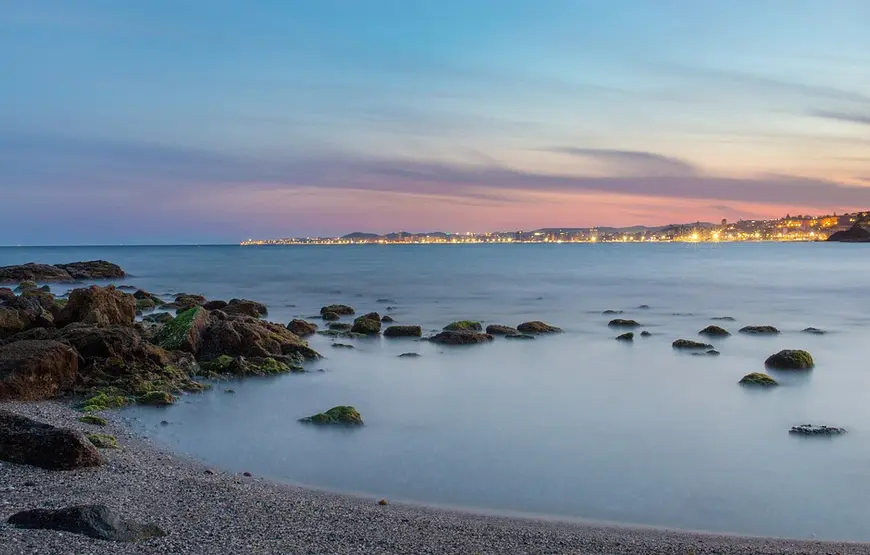 lungo-mare-di-malaga-costa-del-sol-al-tramonto-con-città-sullo-sfondo-illuminata
