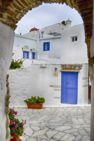facciata-bianca-di-una-casa-con-le-persiane-blu-sotto-un-arco-che-precede-un-cortiletto