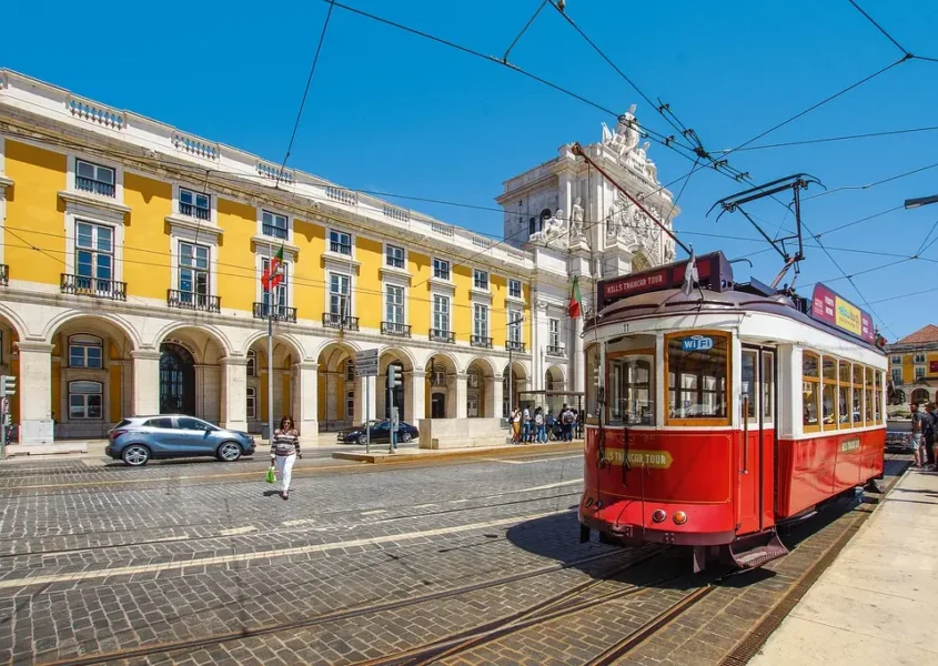 migliori-destinazioni-economiche-estive-d-europa-tram-di-lisbona-fermo-dietro-un-edificio-giallo