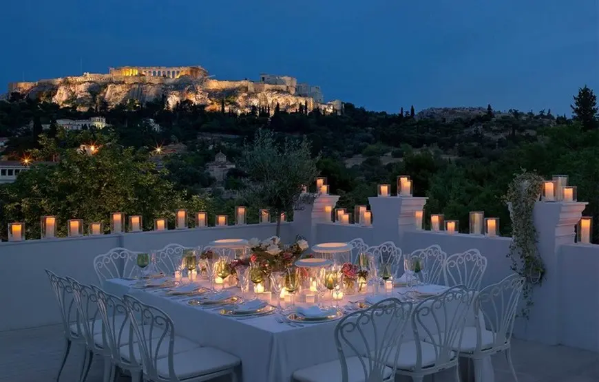 cena-romantica-con-candele-accese-su-una-terrazza-che-guarda-l-acropoli-illuminata-di-sera
